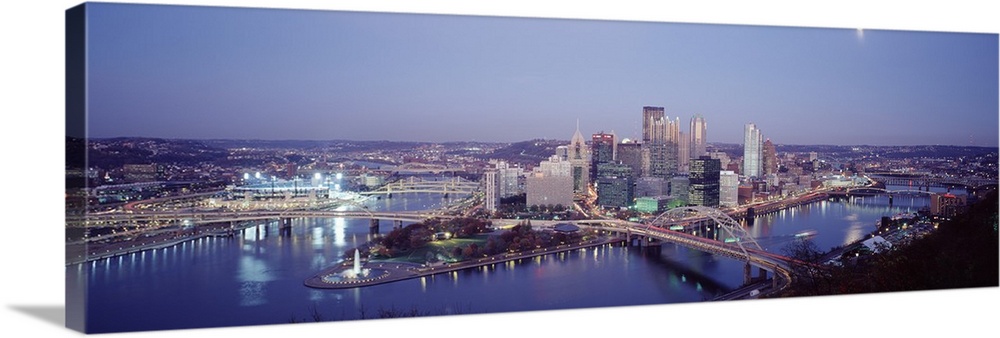 Panoramic photograph of city skyline at dusk.  Iconic buildings, bridges, and waterways are featured.