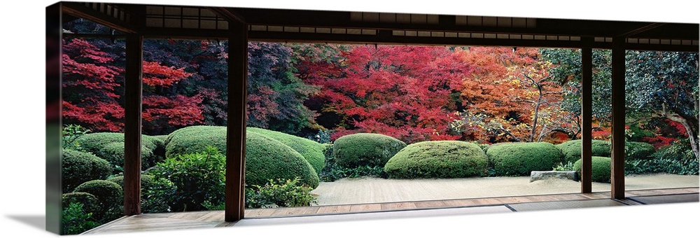 This panoramic photograph is taken from inside a temple and looking out into a forest filled with trees and plants.