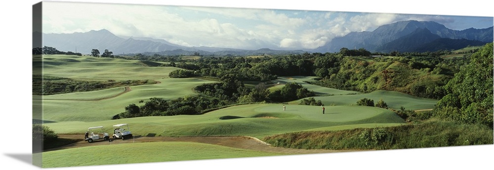 Panoramic picture of rolling hills of a golf course nestled in the Hawaiian mountains.