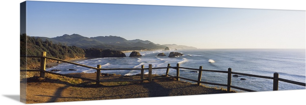 Giant panoramic photograph featuring a railing overlooking Cannon Beach in Oregon (OR) on a sunny day. Large rocks/boulder...