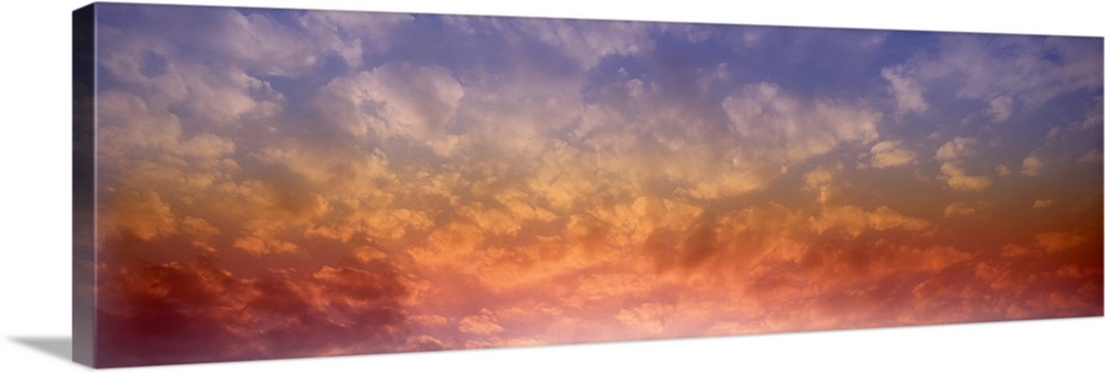 Panoramic photograph of colorful clouds illuminated by the sun.