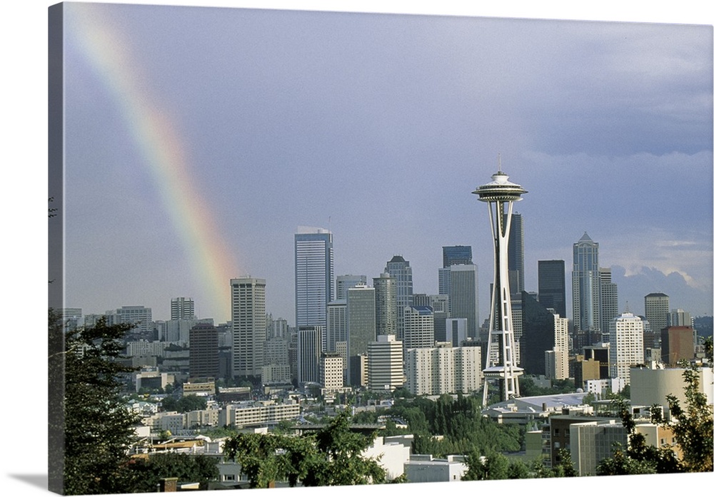 Photograph of a rainbow above the Seattle city skyline on a cloudy day in Seattle, Washington.