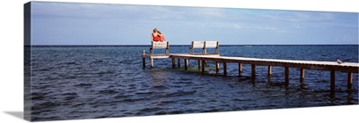 Rear view of mother and her daughter sitting on a bench at a pier, Belize
