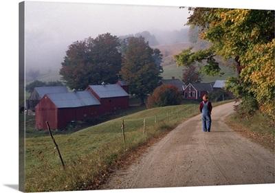 Rear view of person walking down road towards farm, autumn color, Vermont