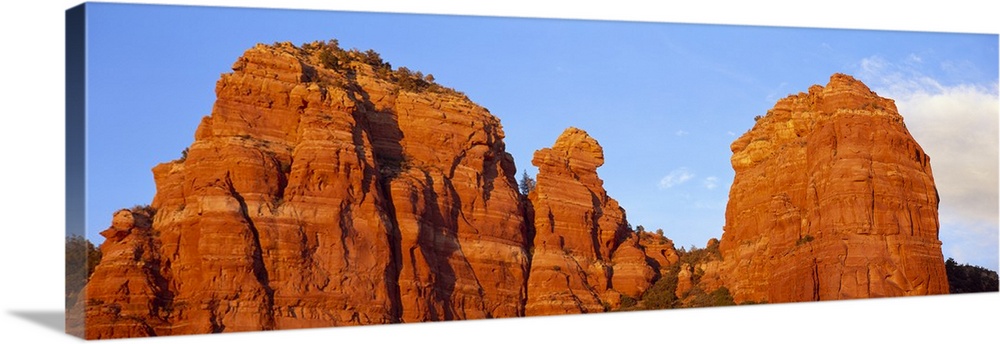 Panoramic photograph of giant rock formations beneath an almost clear blue sky, in Sedona, Arizona.