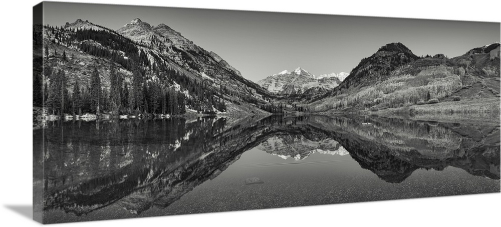Black and white photograph taken of large mountains and terrain that reflect perfectly in the still water below.