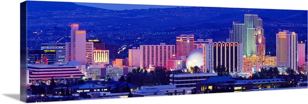 The skyline in Reno is illuminated under a dark sky and photographed in panoramic view.