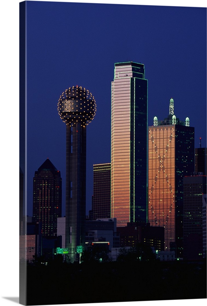 This large vertical piece is a photograph that has been taken of the Dallas skyline with the buildings illuminated under a...