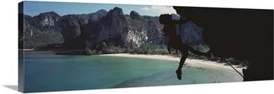 Rock Climber atKrabi, southern Thailand, with Railay beach in background