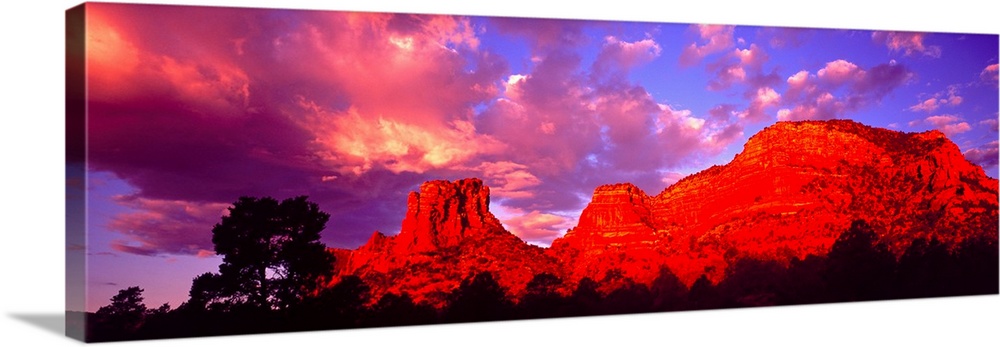 Wide angle photograph on a large canvas of a giant rock formation beneath a vibrant sky at sunset, in Sedona, Arizona.