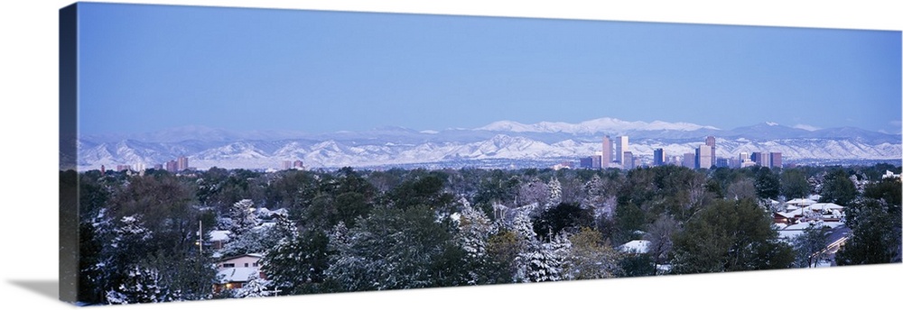 Panoramic photograph on a large wall hanging of a snow covered landscape surrounding houses in front of the city skyline a...