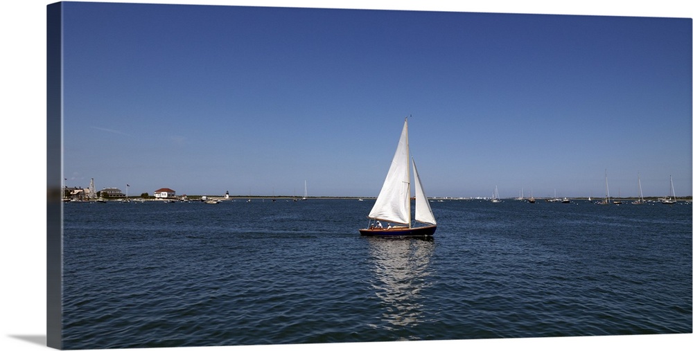 Panoramic photograph of ship in the sea with marina in the distance under a clear sky.