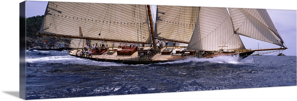 The body of a large sail boat is photographed in wide angle view as one side leans down into the water.