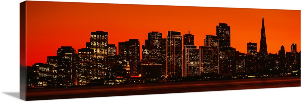 The skyline in San Francisco is pictured in wide angle view with a warm background silhouetting the buildings.