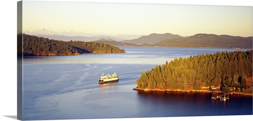 A ferry boat cruises through the sound past the pine tree laden San Juan Islands in Washington State.