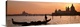 image thumbnail of Panoramic photograph of gondola on waterway with cityscape in background at sunset.