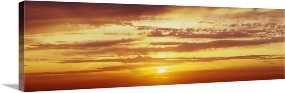 Panoramic photo on canvas of a brightly colored sunset with horizontal clouds.