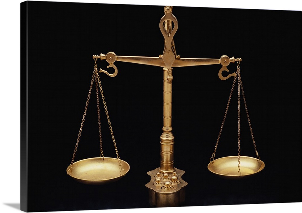 Photograph taken of gold scales of justice against a black background.