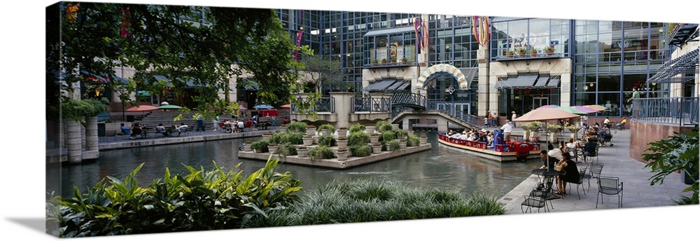 Oversized photograph on a horizontal canvas of the Rivercenter mall in San Antonio, Texas.  A small boat floats through th...