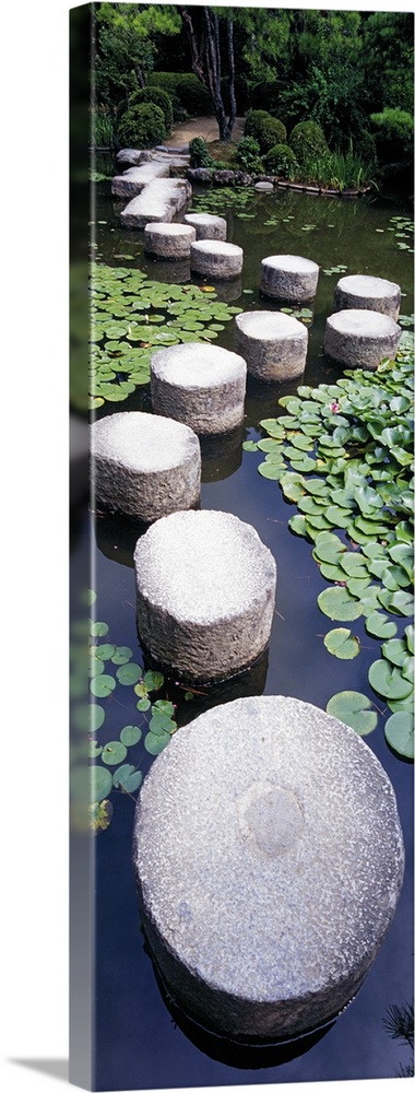 A tall panoramic piece of large stepping stones that create a path through the water in a shrine garden.