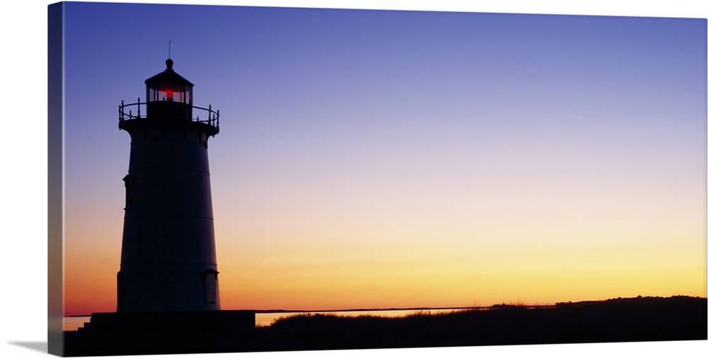 Wall docor of the silhouette of a lighthouse against a bright sunset.