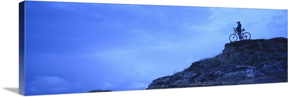 Silhouette of a mountain biker standing on a cliff, Kansas