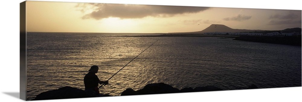 Silhouette of a person fishing in the sea, La Graciosa Island, Canary Islands, Spain