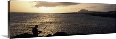 Silhouette of a person fishing in the sea, La Graciosa Island, Canary Islands, Spain