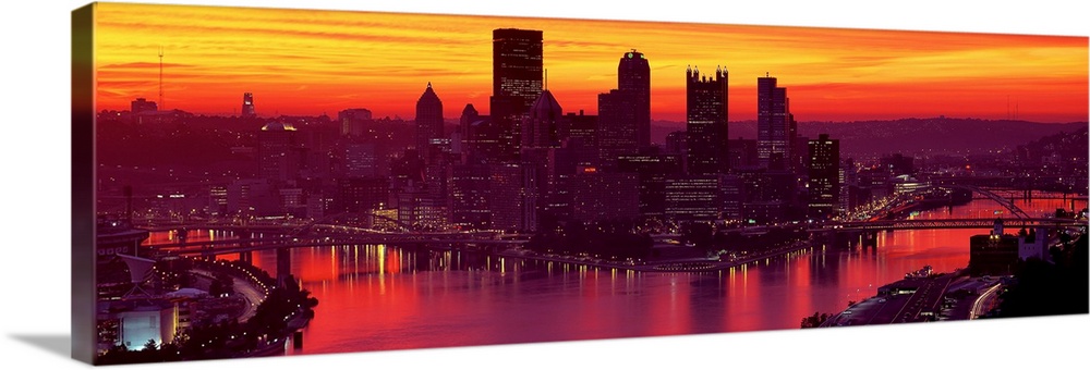 Panoramic photograph of the view of the Pittsburgh skyline from down the Ohio River at sunset and city lights reflecting i...