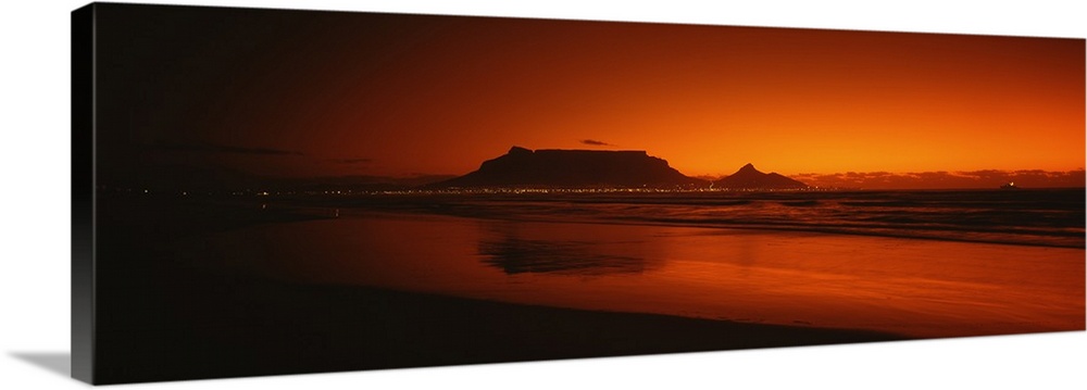 Wide angle, large photograph of sunset at the shoreline near Table Bay in Western Cape Province, South Africa.  The outlin...