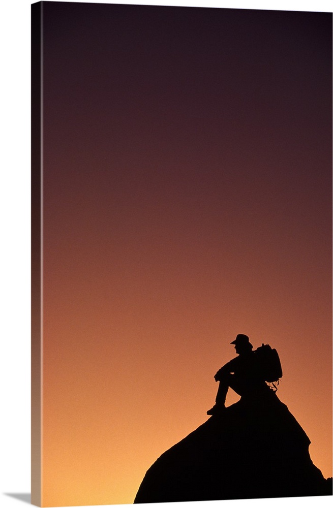 Silhouetted backpacker on rock, sunset light, Utah