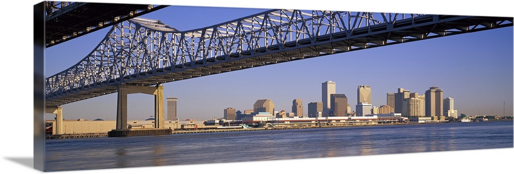 Part of the New Orleans skyline is photographed from a distance below the Crescent City Connection bridge.