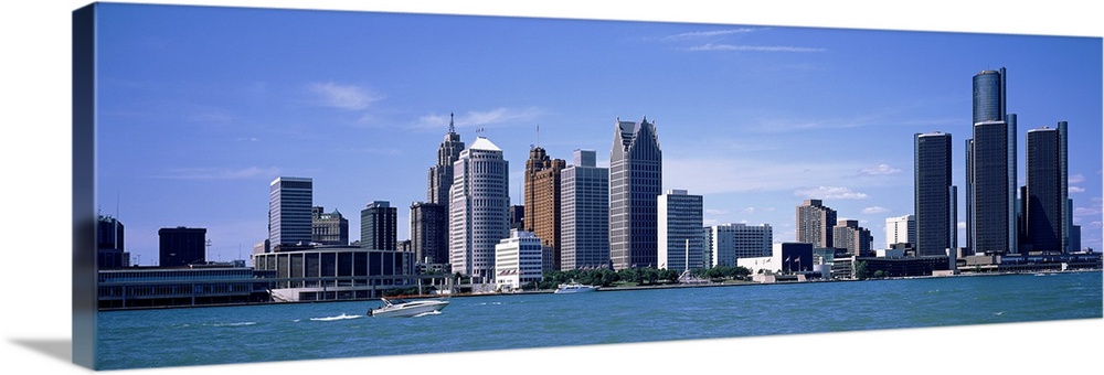 Panoramic photograph taken of the Detroit skyline during the day with a body of water shown in front of the buildings.