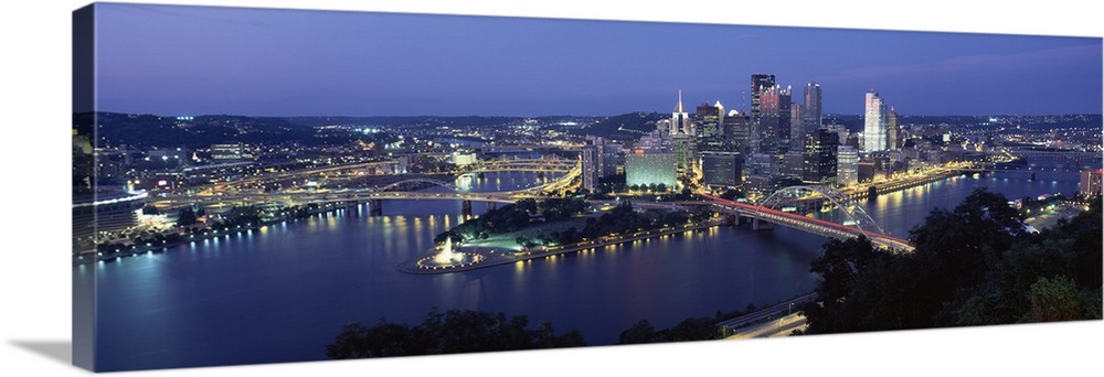 Large panoramic photo of downtown Pittsburgh, Pennsylvania (PA) lit up at night. Multiple bridges visible.