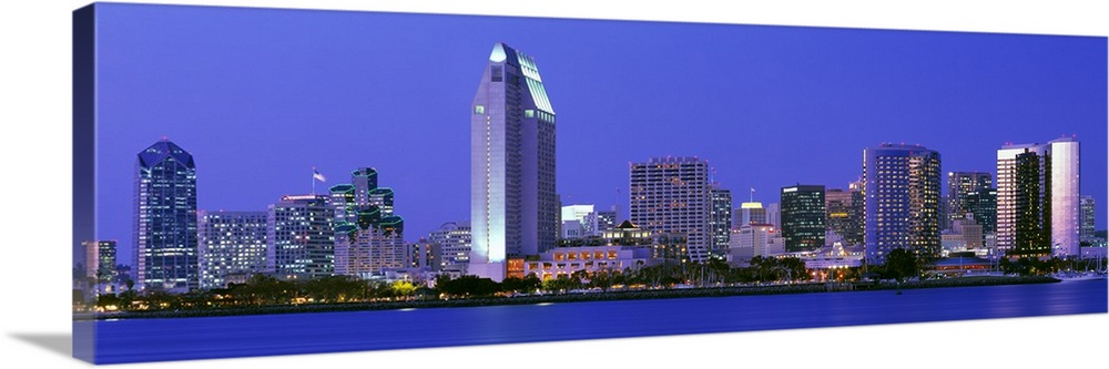 Skyscrapers in San Diego are illuminated and photographed in panoramic view from across a body of water.