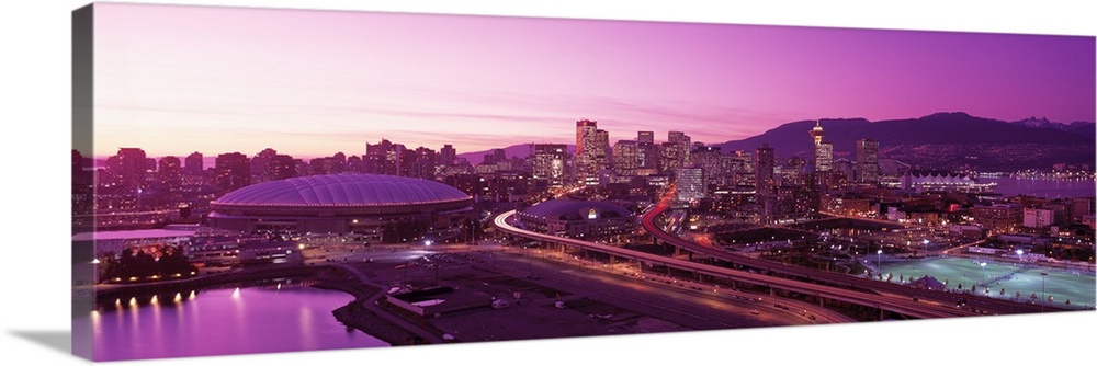 An aerial panoramic photograph taken of the skyline in Vancouver that has a purple hue from the sunset.