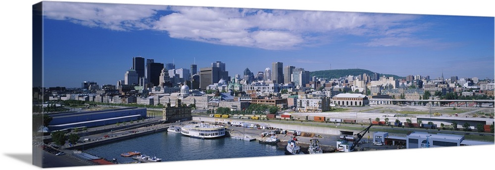 Panoramic photograph of many buildings along the shoreline of Old Port in Montreal, Quebec, Canada.  Many boats sit in the...