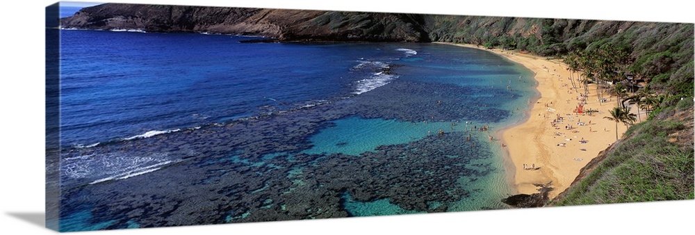 Panoramic photograph of inlet with coral and beach lined with mountains.