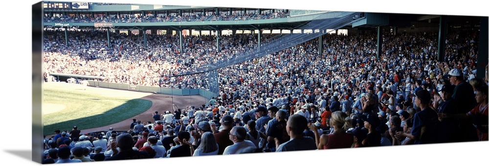 Panoramic, big photograph of packed stands of fans watching a baseball game at Fenway Park, in Boston, Massachusetts.