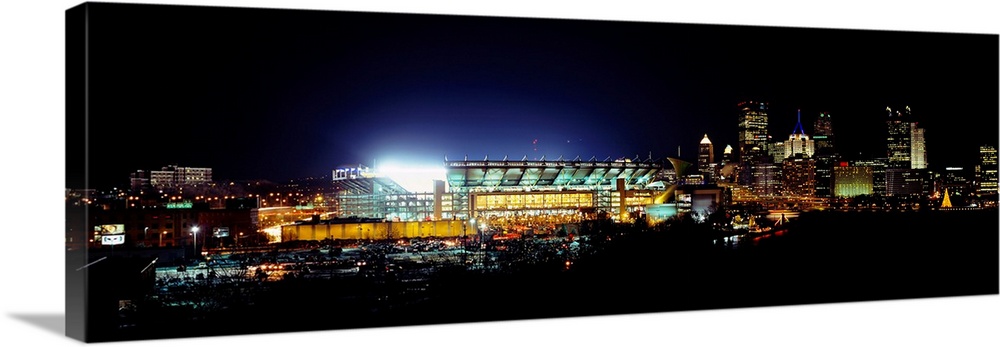 Panoramic photograph of Heinz Field lit up at night as the Steelers play a football game.  The skyscrapers in the backgrou...