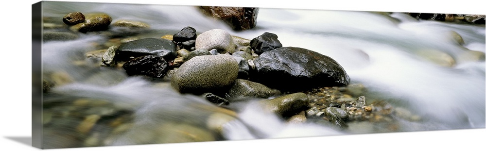 Up-close panoramic photograph of rocky stream with rising mist.