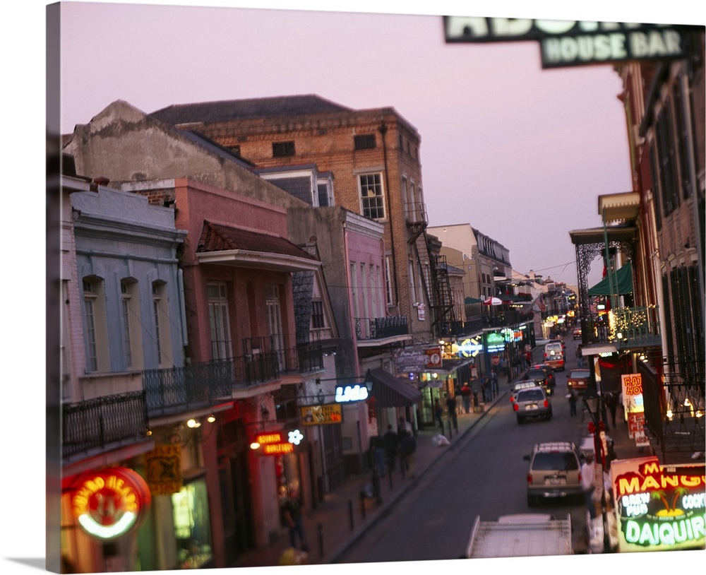 Landscape, large photograph looking down Bourbon Street in New Orleans, Louisiana.  Rows of storefronts with neon signs li...