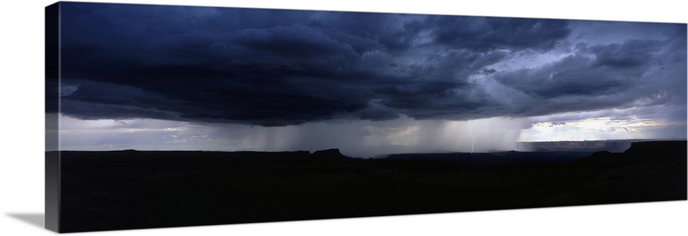 A wide angle shot taken of an immense storm over canyons in Utah.