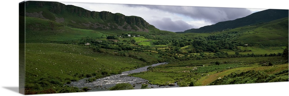 Stream through lush mountain landscape, distant cottages, Ireland