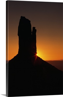 Sunrise behind silhouetted sandstone formation, Monument Valley, Utah