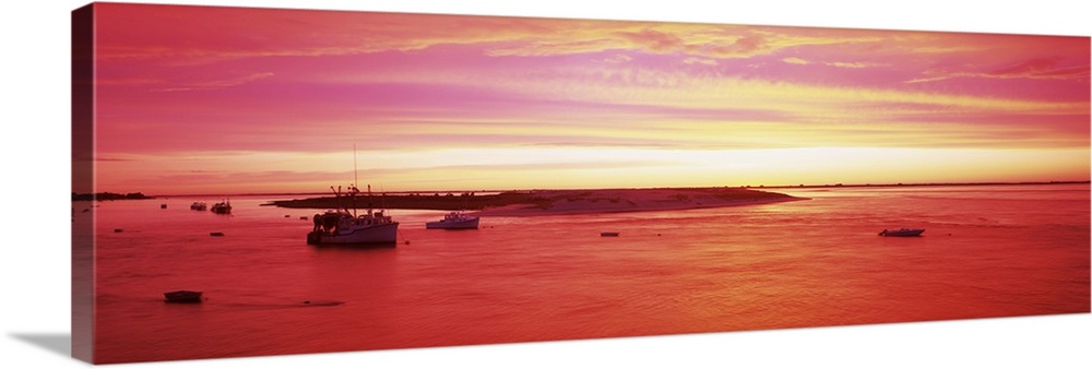 Panoramic image of boats floating in a harbor in Massachusetts while a beautiful sky is painted by the rising sun.