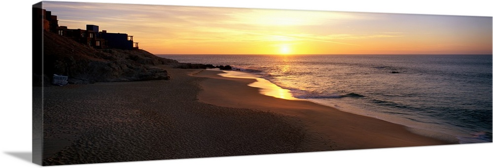 Panoramic photo of the sun rising over the beach in Los Cabos, Mexico.