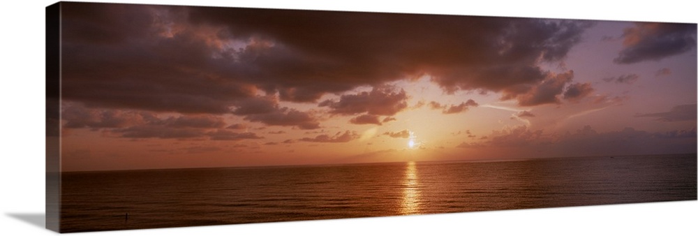 Panoramic photograph of ocean at dawn under a cloudy sky.