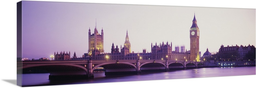 Panoramic photo of Big Ben off in the distance at sunset with a bridge in the foreground.