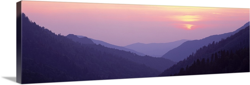 Panoramic photo of rolling mountains in the fog at sunset.